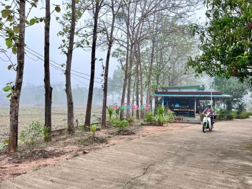 a person riding a scooter down a dirt road at Banromsak resort - บ้านร่มสักรีสอร์ต in Ban Dok Kham Tai (1)
