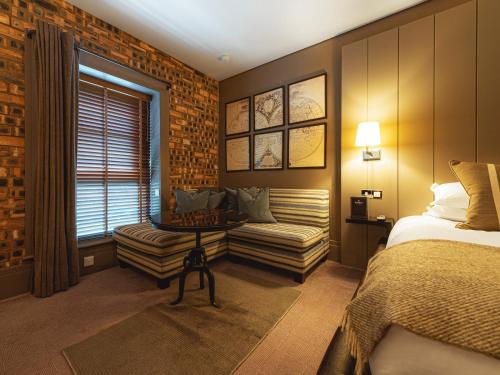 a bedroom with a bed and a couch and a window at Dakota Edinburgh in Queensferry