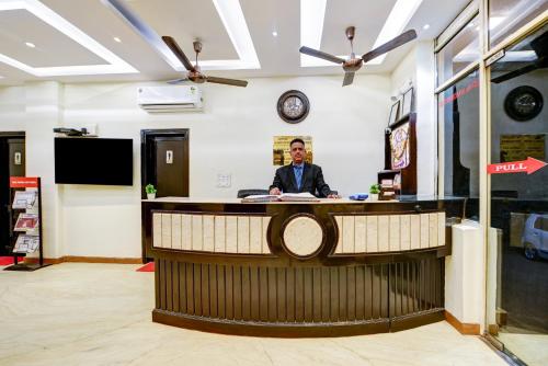a man sitting at a counter in a room at Hotel City Centre Inn Near Nizamuddin Railway Station in New Delhi