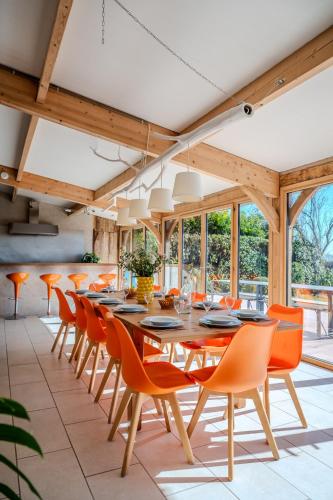 une salle à manger avec une grande table et des chaises orange dans l'établissement Ferme de Brunel- Gîte à la campagne - 13 pers - 1 heure de Paris, à Gressey