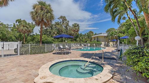 a small pool in a patio with a table and blue umbrellas at Beach Haven in Longboat Key