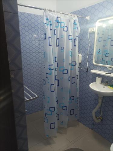 łazienka z zasłoną prysznicową i umywalką w obiekcie Le Studio w mieście Lomé