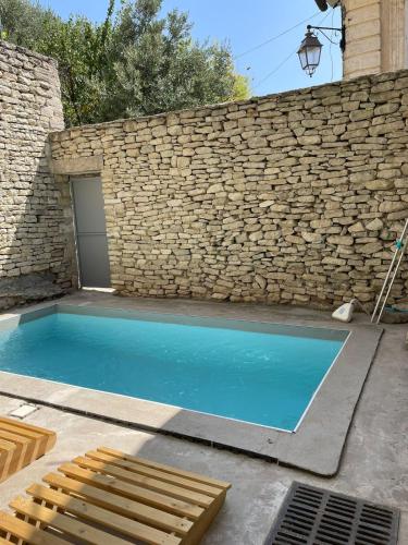 - une piscine en face d'un mur en pierre dans l'établissement Maison exceptionnelle au coeur de Gordes avec piscine privée et vue panoramique, à Gordes