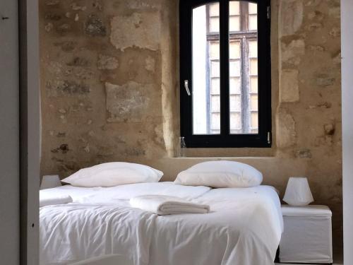 une chambre avec un lit avec des draps blancs et une fenêtre dans l'établissement Maison exceptionnelle au coeur de Gordes avec piscine privée et vue panoramique, à Gordes