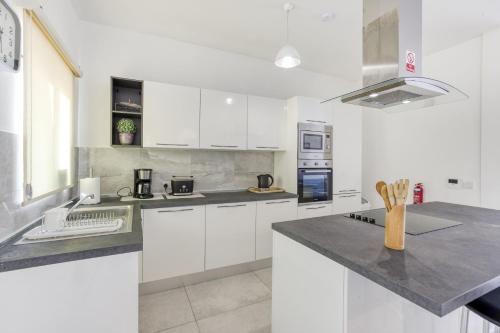a white kitchen with white cabinets and appliances at Fleur de Mai penthouse with large terrace in Gzira in Taʼ Xbiex