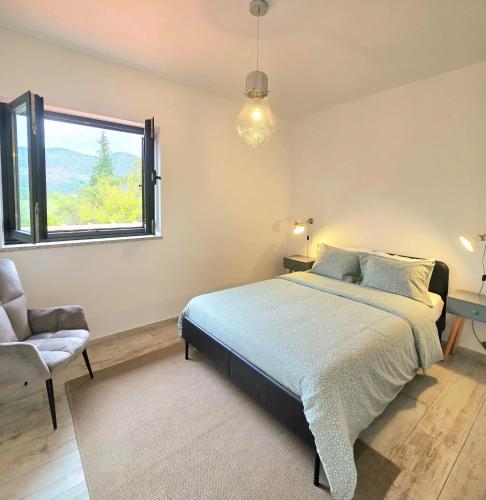 a bedroom with a bed and a chair and a window at Casa Fraga do Suadouro in Campo do Gerês