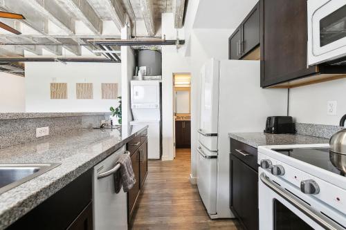 a kitchen with white appliances and wooden floors at Industrial Downtown Apartment - 2BD 2BA in Baton Rouge