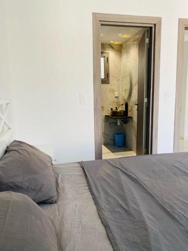 a bedroom with a bed and a bathroom with a sink at La Cascade Ḩammām al Ghazzāz in Kelibia