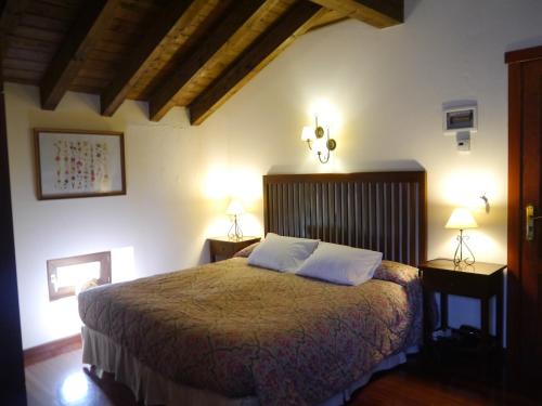 a bedroom with a large bed with two lamps at Posada 3 Valles in Liérganes