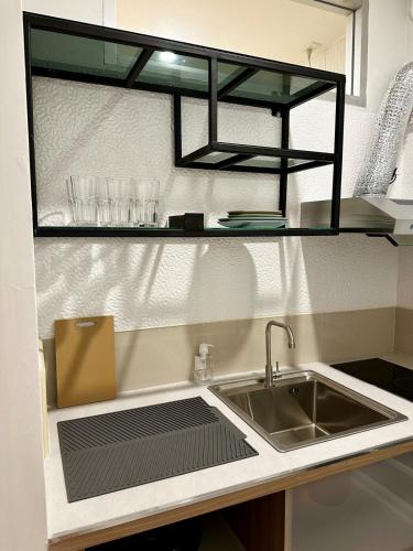 a kitchen counter with a sink and a shelf with glasses at Serene Escape 2 mins from SRT Wat Samien Nari in Bangkok