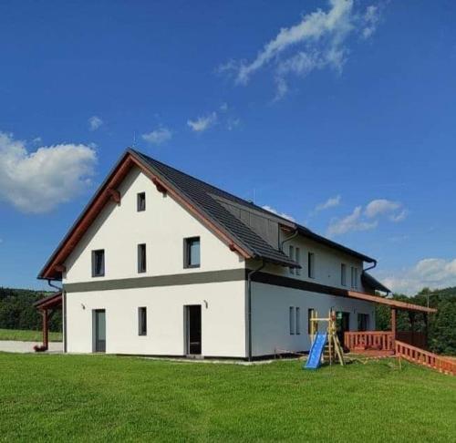 a large white house with a gambrel roof at Penzion Sen Ostružná in Ostružná