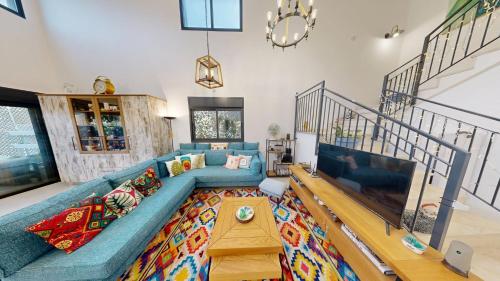 a living room with a blue couch and a tv at The Galilee Flame duplex in Shlomi