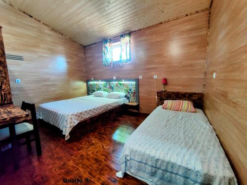 two beds in a room with wooden walls at QT 8 -Casa Amazonia Portugal in Cernache