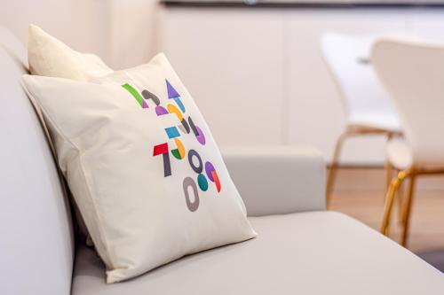 a white couch with a colorful pillow on it at - NumberZ - Rooms Apartments and Suites with Wi-Fi and AC in Borgo Isonzo