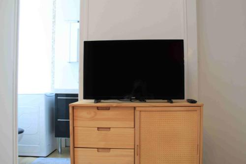 Elle comprend une télévision à écran plat installée au-dessus d'une commode en bois. dans l'établissement Très beau studio proche centre, très calme, à Annecy