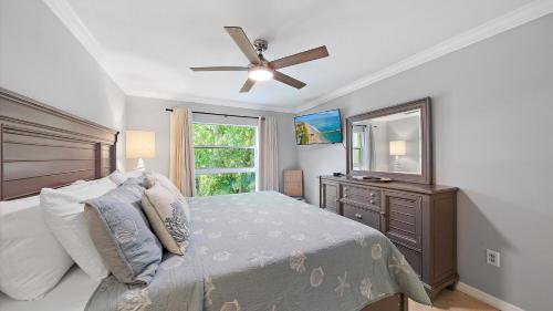 a bedroom with a bed with a ceiling fan and a television at Just Beachy in Longboat Key