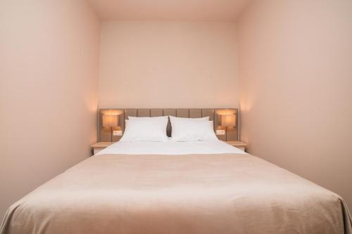 a bedroom with a large white bed with two lamps at Casa Monteiro by Quantique in Braga