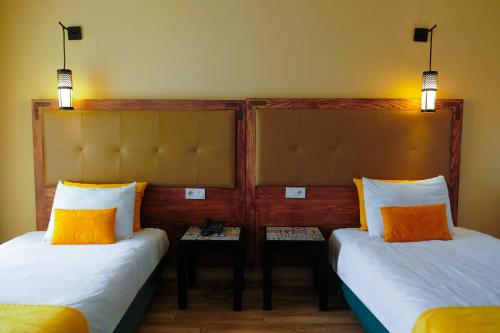 two beds with orange and white pillows in a room at HAMILTON Agadir in Agadir