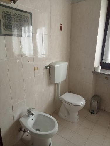 a white bathroom with a toilet and a sink at Un Soggiorno nella Natura in Valperga