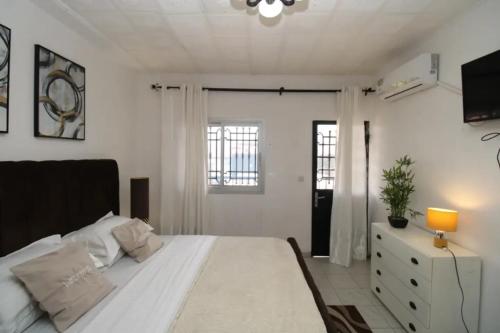 a bedroom with a large white bed and a window at RJS Appart Homey1 avec Jacuzzi in Douala