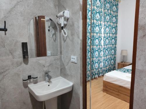 a bathroom with a sink and a mirror and a bed at Sahro Hotel in Bukhara
