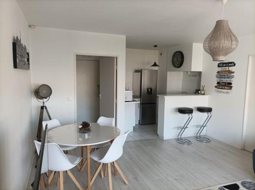 - une cuisine avec une table et des chaises blanches dans la chambre dans l'établissement Family cocoon in Arcachon center, à Arcachon