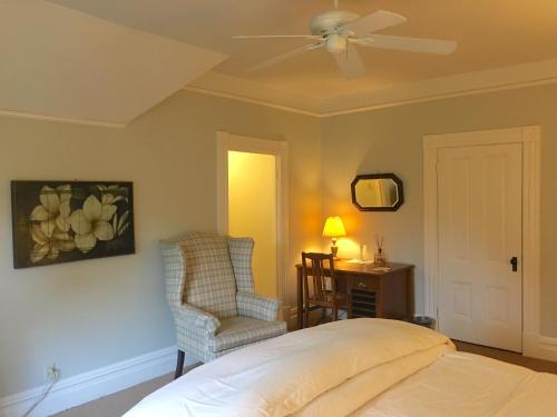 a bedroom with a bed and a chair and a ceiling fan at Cowper Inn in Palo Alto