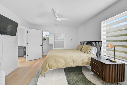 a white bedroom with a bed and a tv at Paradise Found in Sarasota