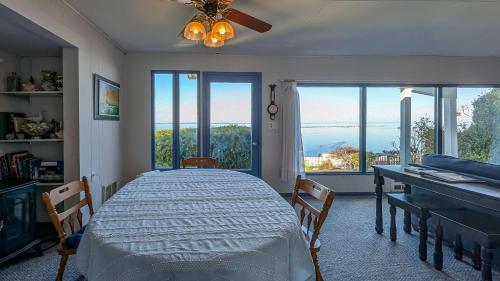 a bedroom with a bed and a desk and windows at PA Crows Nest Cottage in Port Angeles