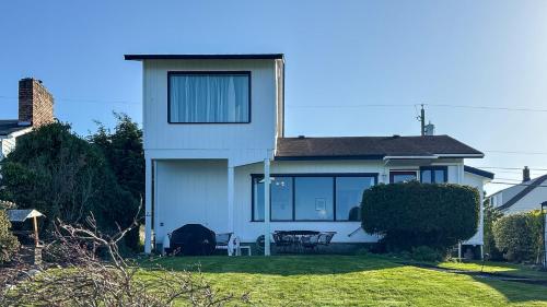 a white house with a table and chairs in the yard at PA Crows Nest Cottage in Port Angeles