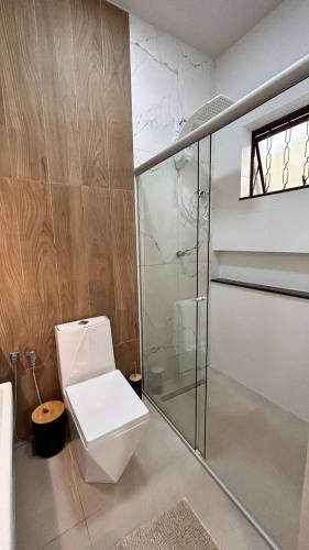 a bathroom with a toilet and a glass shower at Aconchego BH in Belo Horizonte