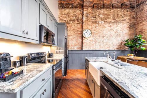 a kitchen with white cabinets and a brick wall at 547 Cherry Loft 201 - The Rookery - Luxe Property in Macon