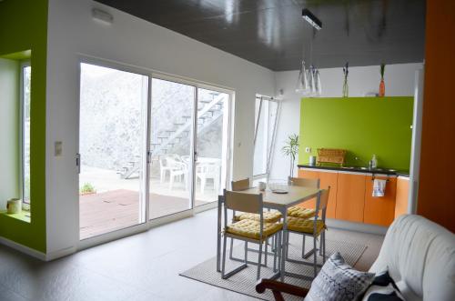 a kitchen with green walls and a table and chairs at A Casa da Ponte in Ribeira Grande