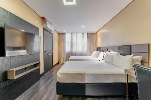 a hotel room with two beds and a flat screen tv at Grand Mercure Curitiba Rayon in Curitiba