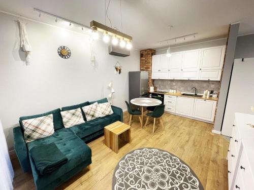a living room with a green couch and a kitchen at Apartament Drugi Dom Sztutowo Baltic Twins in Sztutowo
