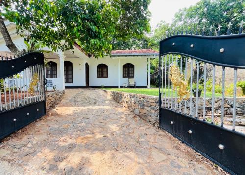 an open gate to a house with a stone fence at Coastal breezy bangalow in Weligama