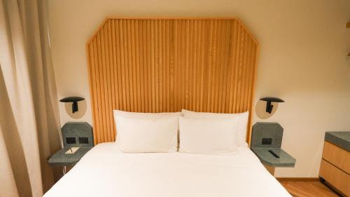 a bedroom with a white bed with a wooden headboard at Rodona Hotel in Mexico City