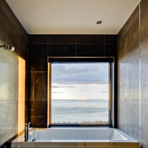 a bathroom with a large window with a bath tub at Villa Marée Basse in La Malbaie