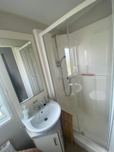 a white bathroom with a sink and a shower at Pebbles Romney Sands in Greatstone