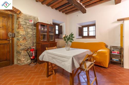 a dining room with a table and a yellow couch at Casa Dei Briganti by TuscanyWeGo in Massa