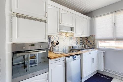 une cuisine avec des armoires blanches et un comptoir dans l'établissement Spacious 2BR Flat near CDG airport, au Blanc-Mesnil