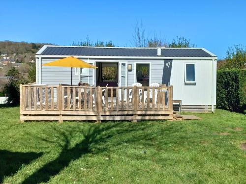 a tiny house with a deck and an umbrella at Mobilhome 4 pers - 2 ch - Centre Aquatique in Houlgate