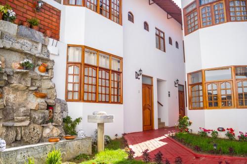 Casa blanca con pared de piedra y puerta en Hotel & Bungalows Villa Valencia en Huaraz