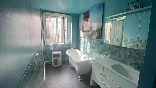 une salle de bain avec une baignoire, un lavabo et un miroir dans l'établissement L'artistique - design & spacieux - Tour Eiffel, à Paris