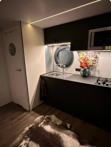 a kitchen with a sink and a counter with a mirror at Exclusieve Houseboat La Mare 12 x 5 meter met sauna en hottup in Maasbommel