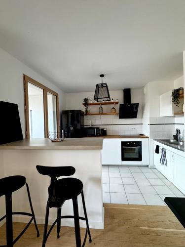 une cuisine avec deux tabourets de bar et un comptoir dans l'établissement Charmant appartement aux portes de Paris, avec Balcon et Parking, à Aubervilliers