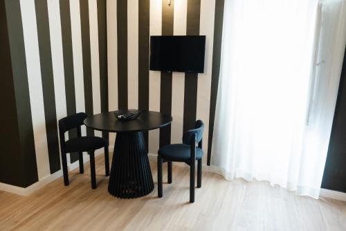 a table and chairs with a television on a striped wall at xenia apartments & suite in Siracusa