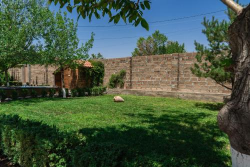 a dog laying in a yard next to a brick wall at Villa Musaler in Musalerr