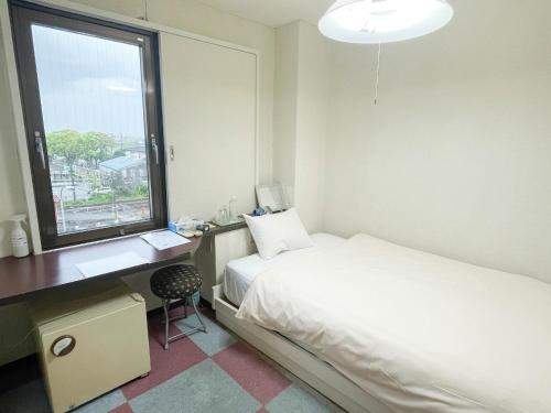 a bedroom with a bed and a desk and a window at Rakuda Hotel Jinguu - Vacation STAY 97183v in Miyazaki