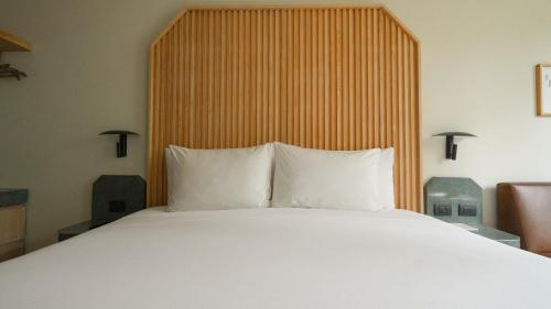 a bed with white pillows and a wooden headboard at Rodona Hotel in Mexico City